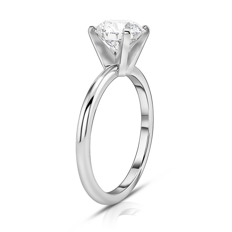 May include: A simple silver band engagement ring with a large, round, clear diamond.