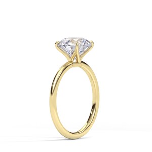 May include: A solitaire engagement ring with a large, clear, round-cut diamond set in a four-prong setting. The band is a polished gold color, and the ring is set against a white background.