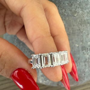 May include: A silver ring with four emerald-cut diamonds set in a row.