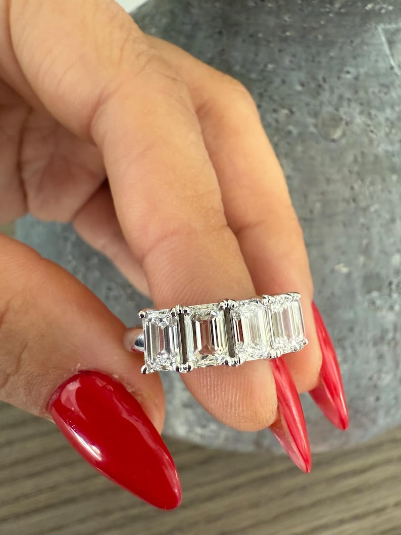 May include: A silver ring with four emerald-cut diamonds set in a row.