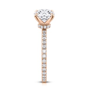 May include: A rose gold engagement ring with a round center stone and a pave diamond band.