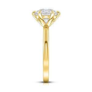 May include: A gold engagement ring with a large, round, clear center stone and two smaller, triangular stones on either side. The ring has a simple band.