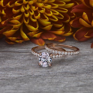 May include: A rose gold engagement ring set with a large oval-shaped diamond and a matching band with smaller diamonds.