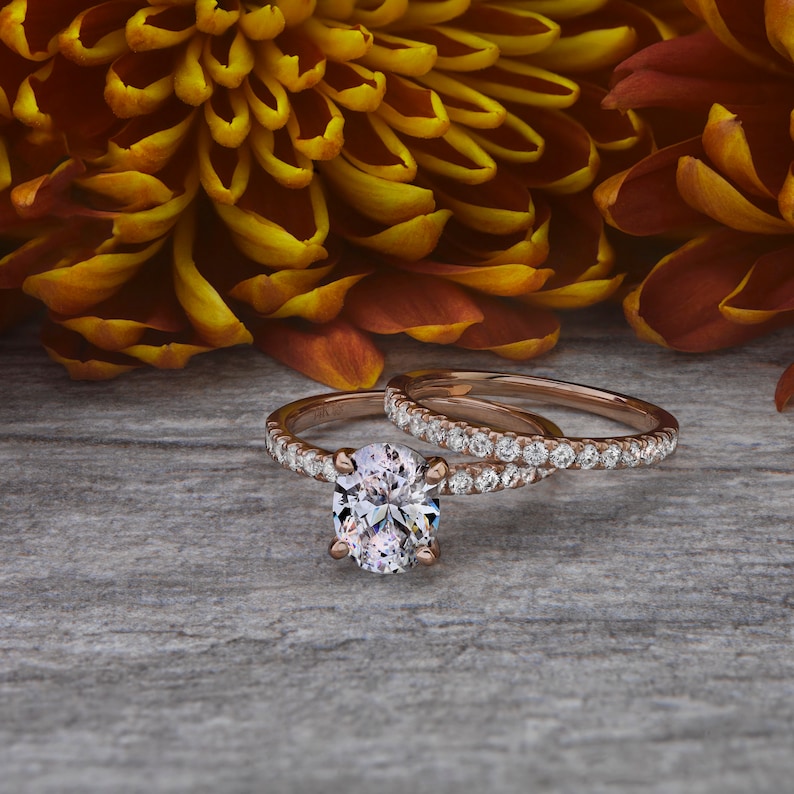 May include: A rose gold engagement ring set with a large oval-shaped diamond and a matching band with smaller diamonds.
