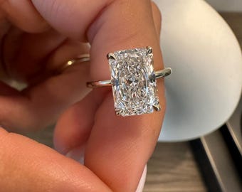 Può includere: Un anello d'oro con un grande diamante rettangolare trasparente.