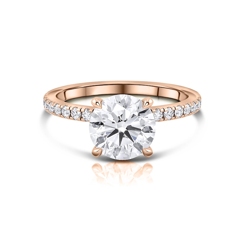May include: A rose gold engagement ring with a round brilliant cut diamond center stone and a pave diamond band.