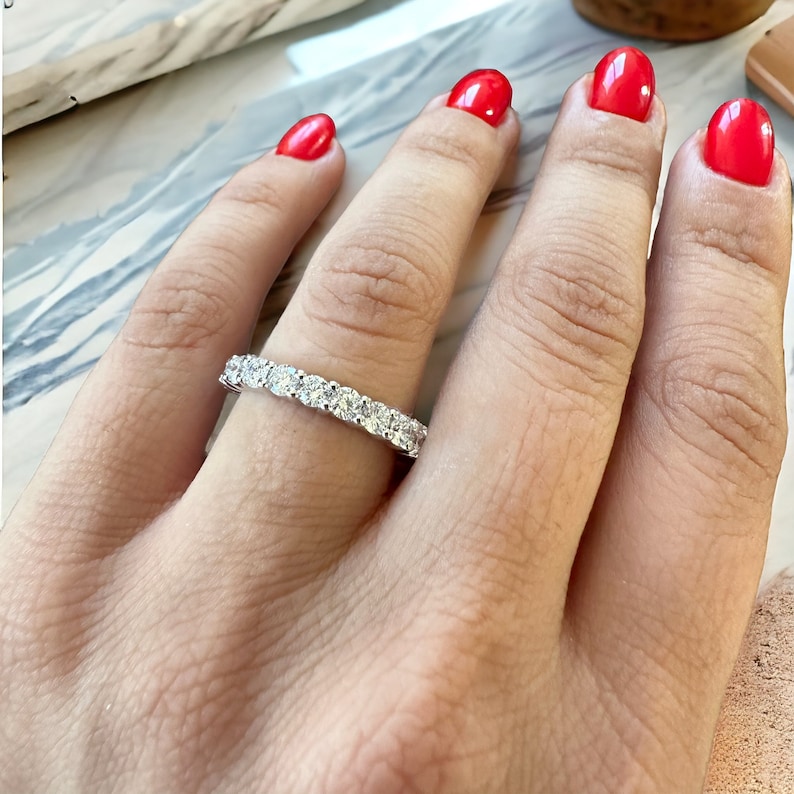 May include: A silver band ring with a row of small, clear, round gemstones.