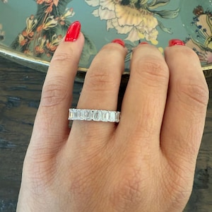 May include: A silver band ring with a row of emerald-cut diamonds.