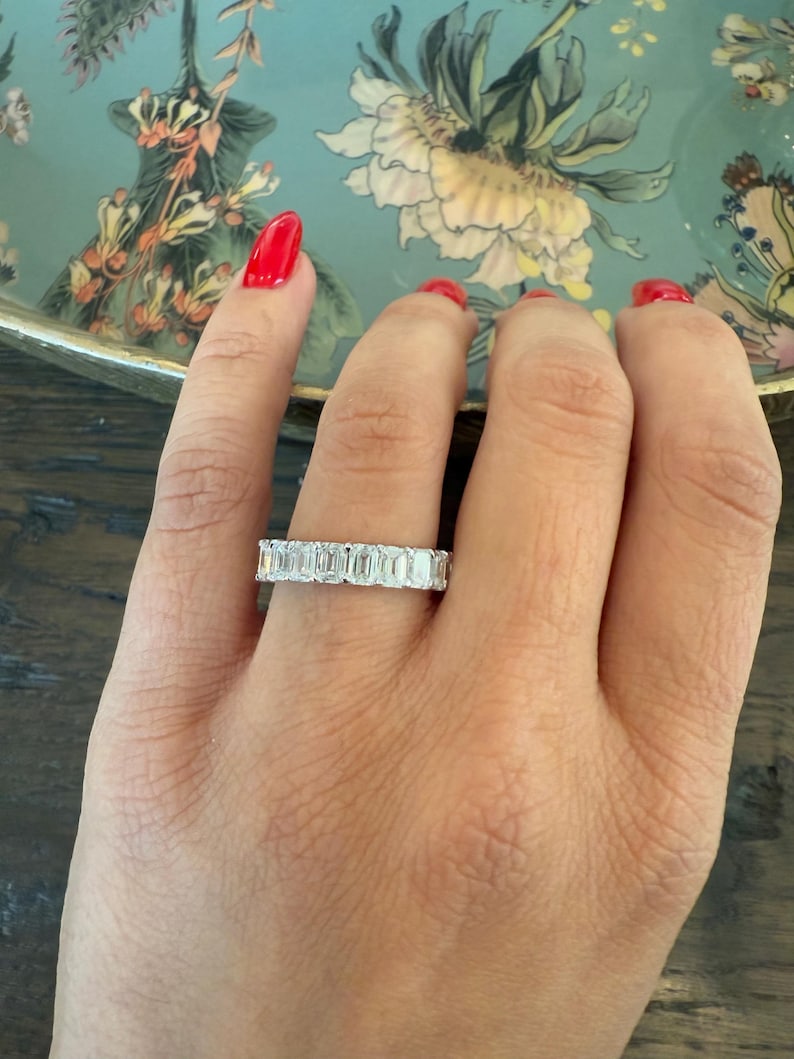 May include: A silver band ring with a row of emerald-cut diamonds.