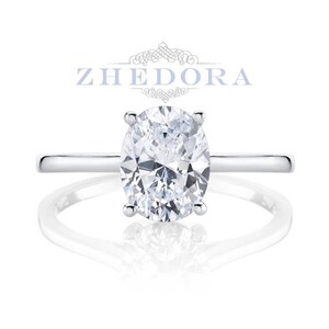 Puede incluir: Un anillo de compromiso de plata con un gran diamante de forma ovalada.