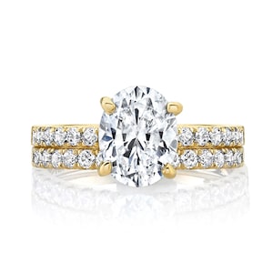 May include: A gold engagement ring set with a large oval-shaped diamond and two smaller diamond bands.