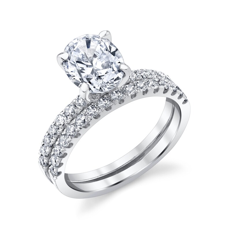 May include: A silver engagement ring set with a large oval-shaped center stone and a matching band with smaller stones set in a pave setting.