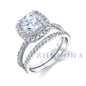 May include: A silver engagement ring set with a cushion-cut center stone and a halo of smaller stones. The band is also set with smaller stones.