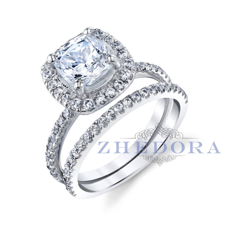 May include: A silver engagement ring set with a cushion-cut center stone and a halo of smaller stones. The band is also set with smaller stones.