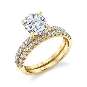 May include: A gold engagement ring set with a large oval-shaped diamond and a matching band with smaller diamonds.