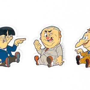 May include: Three cartoon stickers featuring characters from the classic comedy show "The Three Stooges." The stickers are white with a black outline and feature the characters Moe, Larry, and Curly. Moe is wearing a blue suit and has a stern expression on his face. Larry is wearing a gray suit and has a mischievous grin. Curly is wearing a brown suit and has a wide-eyed, surprised expression.