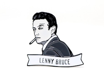 May include: A black and white enamel pin featuring a portrait of Lenny Bruce, with a cigarette in his mouth. The pin has a banner with the name "LENNY BRUCE" in black text on a white background.