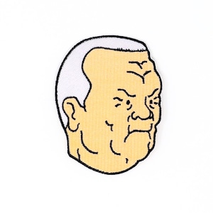 May include: An embroidered patch of a cartoon man with white hair, a furrowed brow, and a grumpy expression.