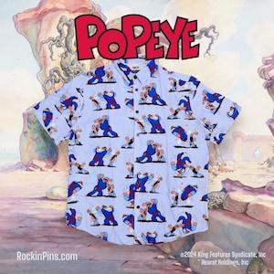 May include: A light blue short-sleeved button-up shirt with a repeating pattern of Popeye and Bluto fighting. The shirt has a white collar and buttons. The text "Popeye" is printed in red at the top of the image.
