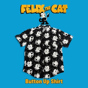 Op de afbeelding: Een zwart overhemd met korte mouwen en knoopsluiting, voorzien van een all-over witte grafische print van Felix de Kat-gezichten. Boven het overhemd staat de tekst FELIX THE CAT met een illustratie van het personage met een banjo. Onderaan staat Button Up Shirt.
