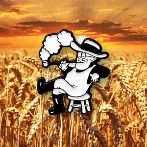 May include: Black and white enamel pin of a cartoon farmer wearing a hat and smoking a pipe. The farmer is sitting on a stool in a field of wheat.