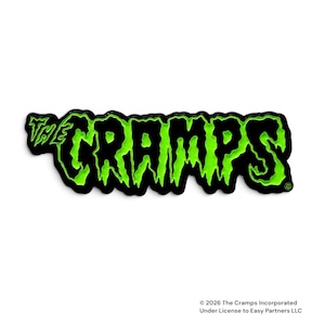 Op de afbeelding: Een zwart en neon-groene emaille speld met de tekst THE CRAMPS in een gestileerd, druipend, op horror geïnspireerd lettertype. Het ontwerp heeft een zwarte omlijning en een copyright-symbool in de rechterbenedenhoek, op een witte achtergrond.