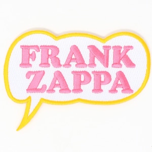 May include: A white embroidered patch with a yellow outline in the shape of a speech bubble. The text inside the speech bubble reads "FRANK ZAPPA" in pink.