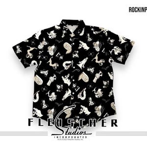 May include: Black short-sleeved button-up shirt with a white print of various cartoon characters and objects. The shirt has a collar and a button-up front. The print includes a dragon, a ghost, a heart, a key, a crown, and a musical note. The shirt has the text "Fleischer Studios Incorporated" at the bottom.