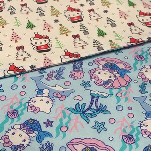 May include: Two fabric swatches with different patterns. The top swatch is white with a repeating pattern of a cartoon cat wearing a Santa hat and a Christmas tree. The bottom swatch is light blue with a repeating pattern of a cartoon cat wearing a seashell and a mermaid tail, a dolphin, and a palm tree.