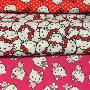 May include: Three pieces of fabric with a Hello Kitty print. The top fabric is red with white polka dots and white Hello Kitty faces. The middle fabric is white with red Hello Kitty faces. The bottom fabric is pink with white Hello Kitty faces.