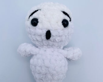 May include: A white crocheted ghost plush toy with black eyes and a surprised expression.