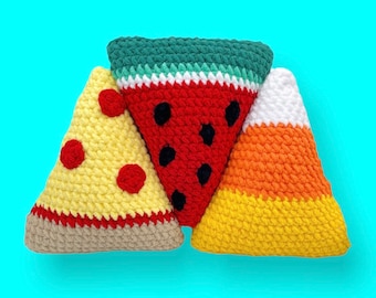 Könnte beinhalten: Drei gehäkelte dreieckige Kissen in Form einer Wassermelone, einer Pizza und eines Mais-Bonbons. Das Wassermelonenkissen ist rot und grün mit schwarzen Kernen. Das Pizzakissen ist gelb mit rotem Pepperoni. Das Mais-Bonbon-Kissen ist orange, gelb und weiß.