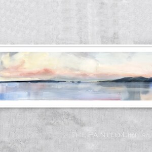 May include: A watercolor painting of a seascape with a pink and yellow sunset over a calm body of water. The painting is framed in a white frame.
