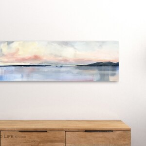 May include: A watercolor painting of a landscape with a pink and yellow sky, a dark blue line representing water, and a dark blue mountain range in the distance.