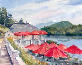 May include: Watercolor painting of a lakeside restaurant with red umbrellas. The building has a dark roof and white trim. Lush green trees and a mountain range are in the background. The water reflects the sky and surrounding landscape.