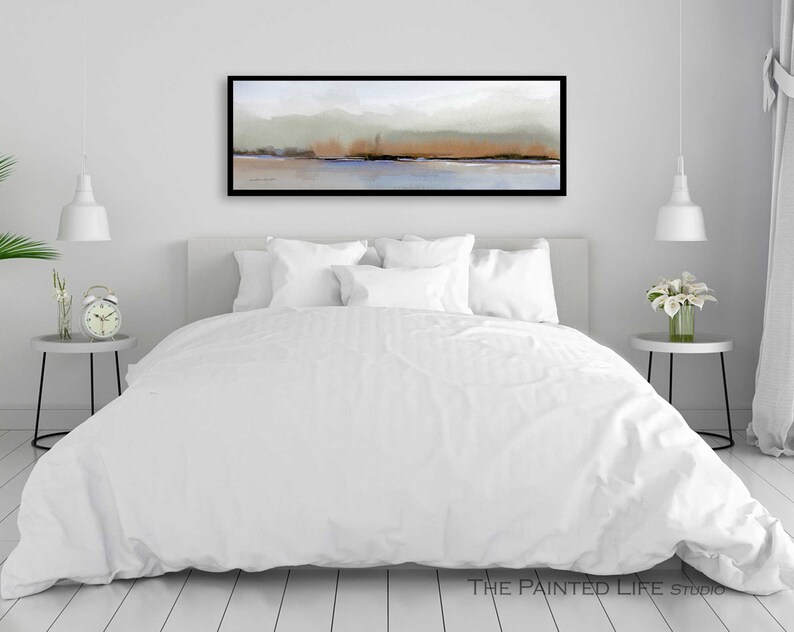Puede incluir: Una cama blanca con un edred&oacute;n blanco y almohadas blancas en un dormitorio con una pared blanca y una pintura abstracta de paisaje enmarcada en negro sobre la cama.