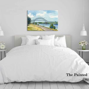 May include: Watercolor painting of a bridge over a river, with blue skies and green trees. The artwork is displayed above a bed with white bedding. The Painted Life Studio is printed on the bottom right.