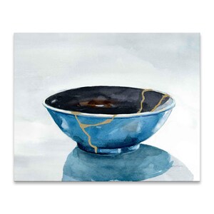 May include: A blue ceramic bowl with gold cracks. The bowl is sitting on a white surface and is reflecting light.