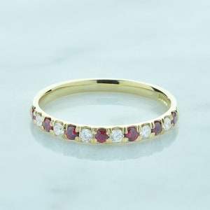 May include: A gold band ring with alternating red rubies and white diamonds.