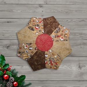May include: A quilted, star-shaped table topper with a red center and various brown and tan patterned segments. The patterns include cat-themed designs and textured fabrics. The topper is designed for decorative use.