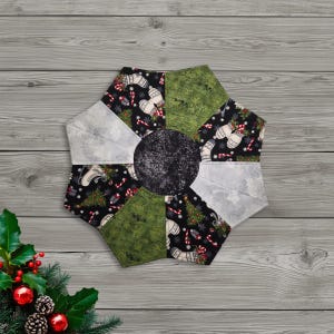 May include: A quilted Christmas tree skirt with a central black circle and a starburst design. The skirt features panels of black fabric with Christmas motifs, green patterned fabric, and silver-gray fabric. Festive holiday decor.