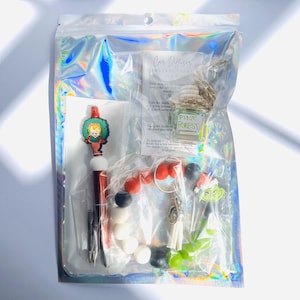 Puede incluir: Una bolsa de plástico transparente llena de accesorios para el coche con temática navideña. La bolsa incluye un personaje Grinch rojo y blanco, un bolígrafo rojo y blanco con un adorno de árbol de Navidad, una pequeña botella de difusor de coche "Pine Forest" y una cadena de cuentas rojas, blancas y negras.