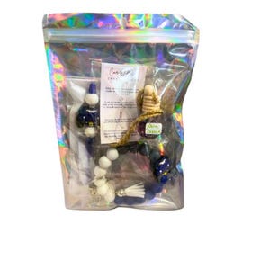 Könnte beinhalten: Ein blaues und weißes Auto-Lufterfrischer-Set mit einem Quasten, Perlen und einer kleinen Flasche ätherischem Öl. Das Set wird mit einer Anleitung zur Verwendung geliefert. Die Verpackung ist aus klarem Kunststoff mit einem holografischen, irisierenden Finish.