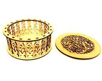 May include: A wooden box with a round, intricate design. The box is open and the lid is sitting next to it. The lid has a similar design to the box.
