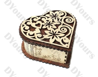 Puede incluir: Una caja de madera en forma de corazón con un delicado diseño floral recortado en la parte superior. La caja está hecha de madera oscura y tiene un interior de madera clara.