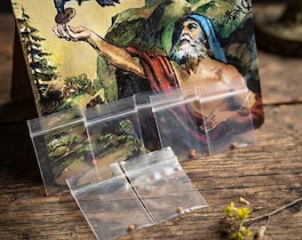 Op de afbeelding: Een rechthoekige kaart met een kleurrijke illustratie van een bebaard figuur met een blauwe hoofdbedekking en een rode mantel die naar een vliegende zwarte vogel reikt, geplaatst achter verschillende kleine, doorzichtige, lege plastic zakjes.