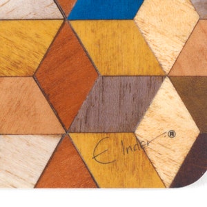 May include: Close-up of a wooden coaster with a geometric pattern. The design features various wood tones, including shades of brown, yellow, and blue, arranged in a repeating diamond shape. The coaster has a white border and the text "E Inder".