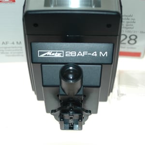 May include: A black Metz 28 AF-4 M flash unit with a built-in flash diffuser and a hot shoe mount.