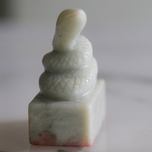A 127g carved jade stamp in the shape of a snake in a box with a pot of red ink