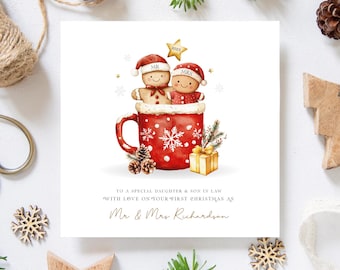 May include: A Christmas card with a red mug design, holding gingerbread people wearing Santa hats. The mug is decorated with snowflakes and the words "Mr" and "Mrs". The card includes the text "To a special daughter & son in law" and "With love on your first Christmas as Mr & Mrs Richardson".